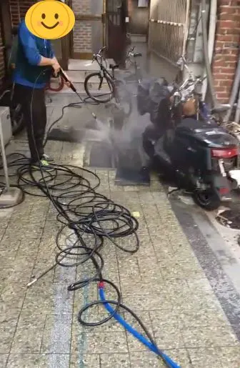 골목 바닥 배수구에 고압세척 중인 작업자